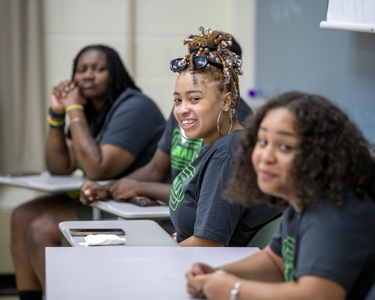 A LINKS student smiles at their desk 