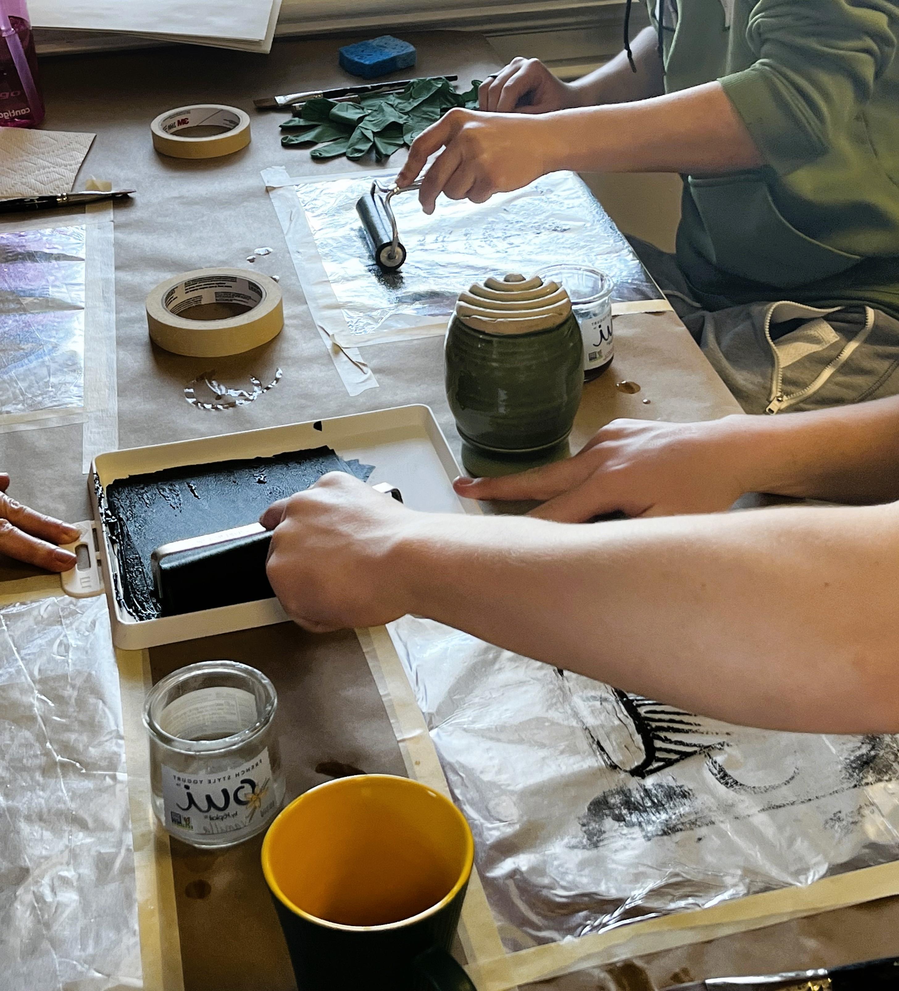 People sitting at table applying ink with rollers