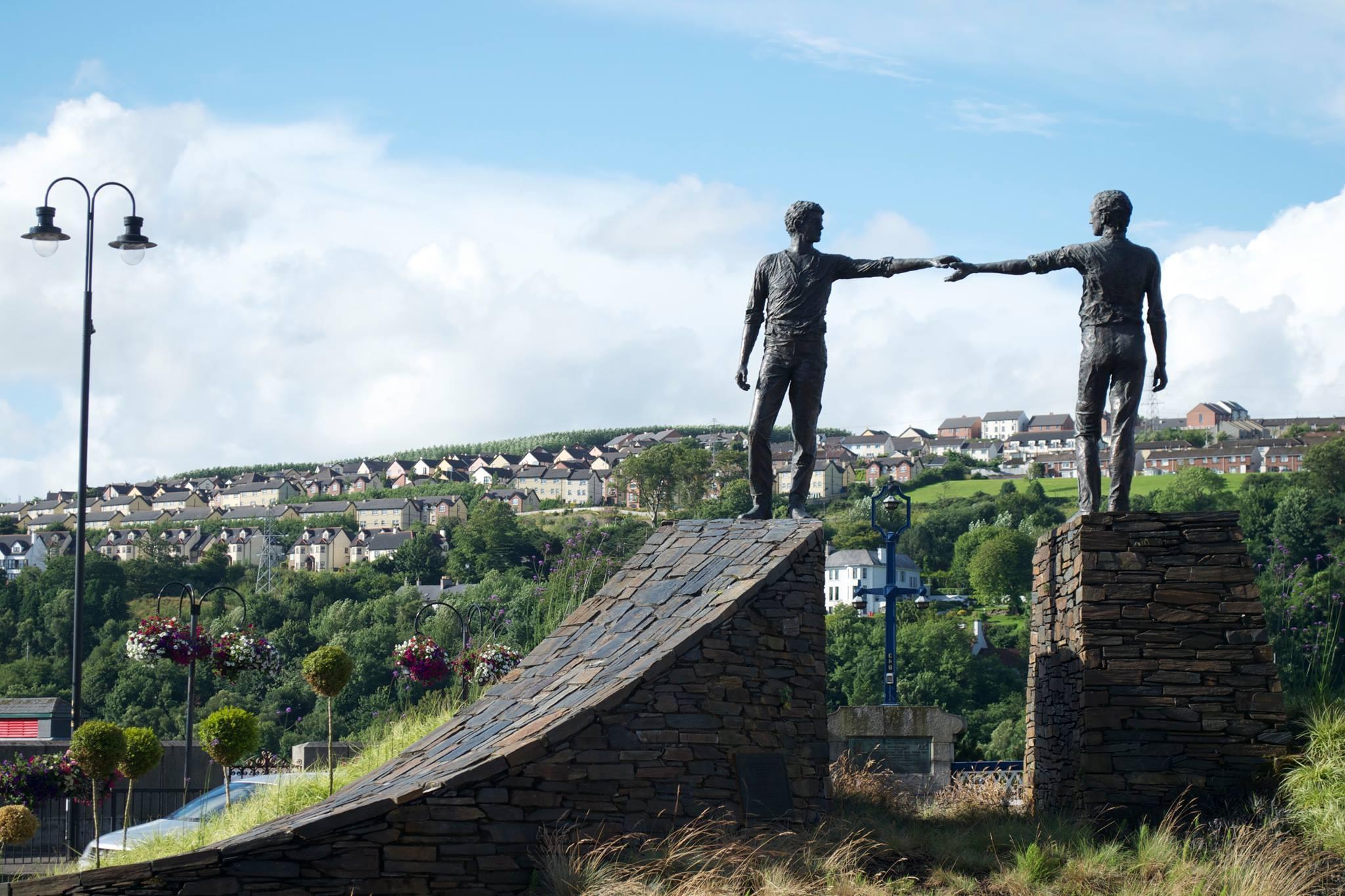 Two statues of people nearly touching hands