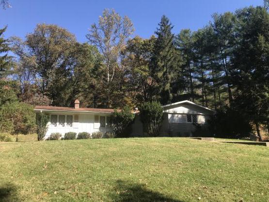 Ranch-style house with lawn in front and trees in back