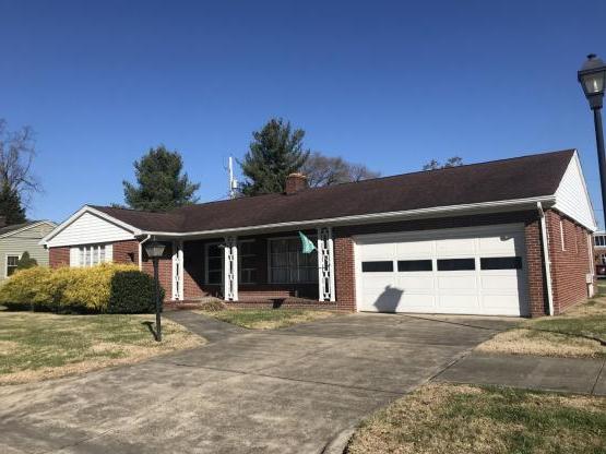 Front of brick ranch-style house with garage and driveway, and a front porch